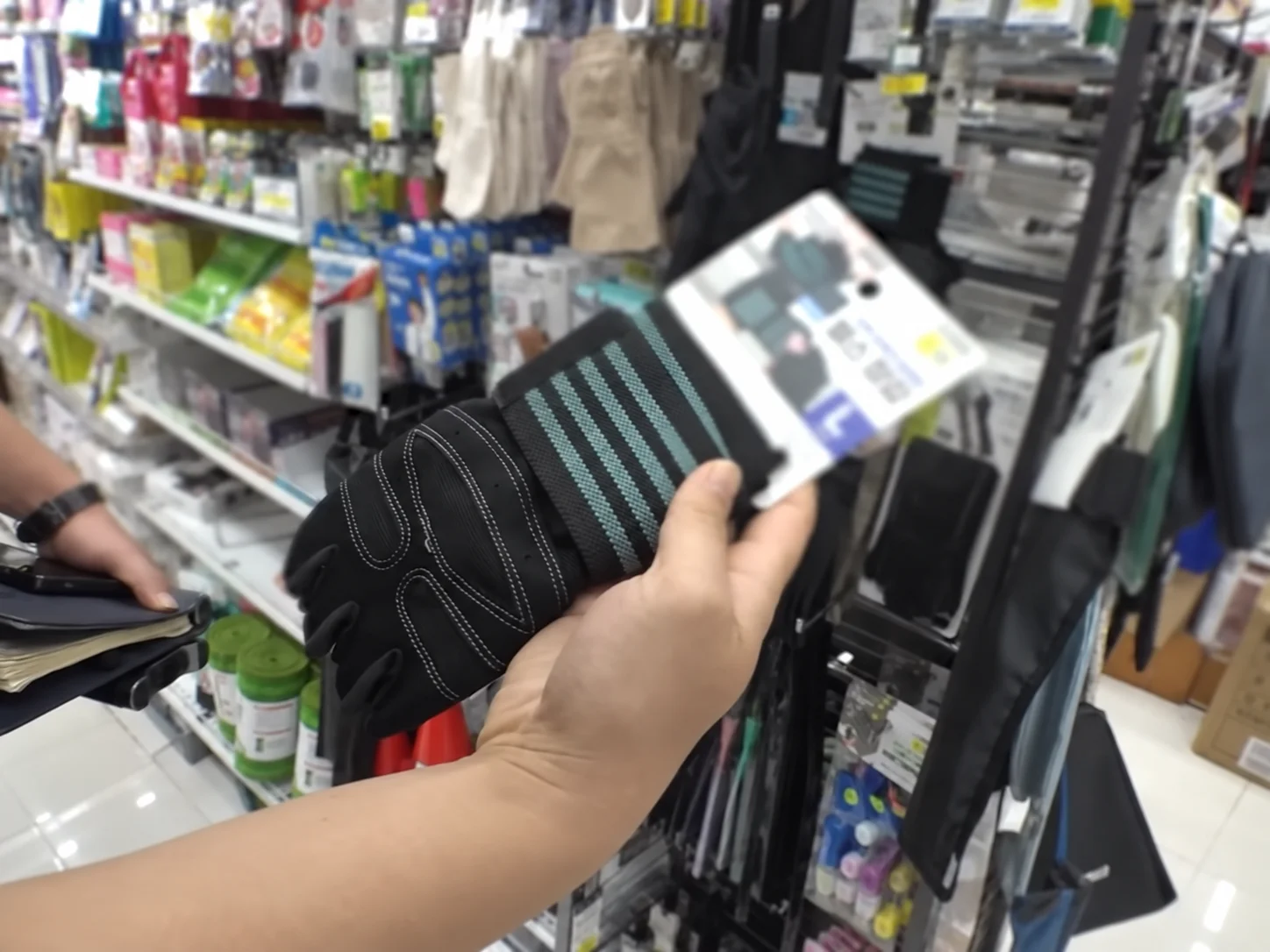 A hand holding a pair of anti-slip gloves in a store