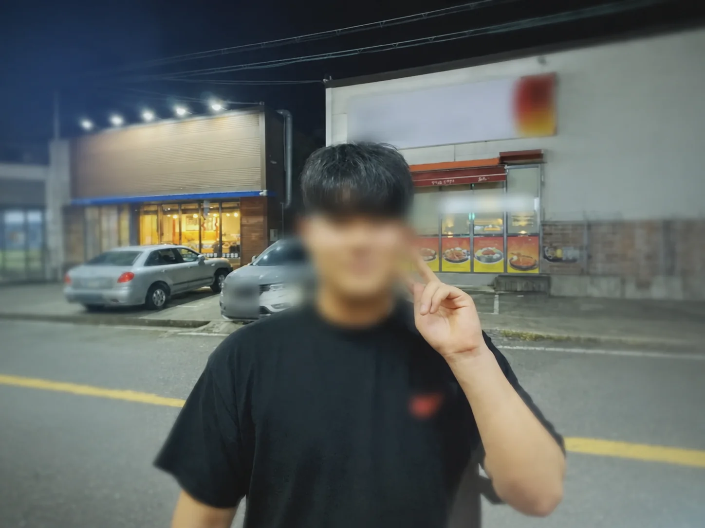 Gyeongjun Park standing outside at night making a peace sign