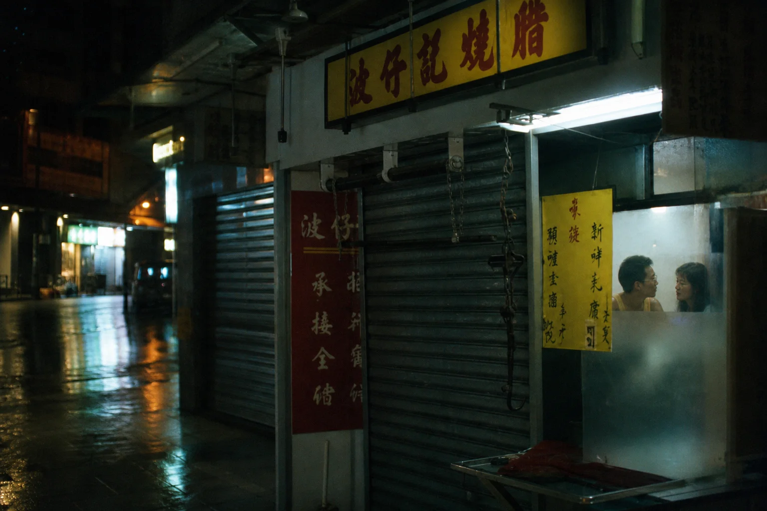 A man and a woman sitting close together inside a Hong Kong barbecue shop at night, its shutters pulled down